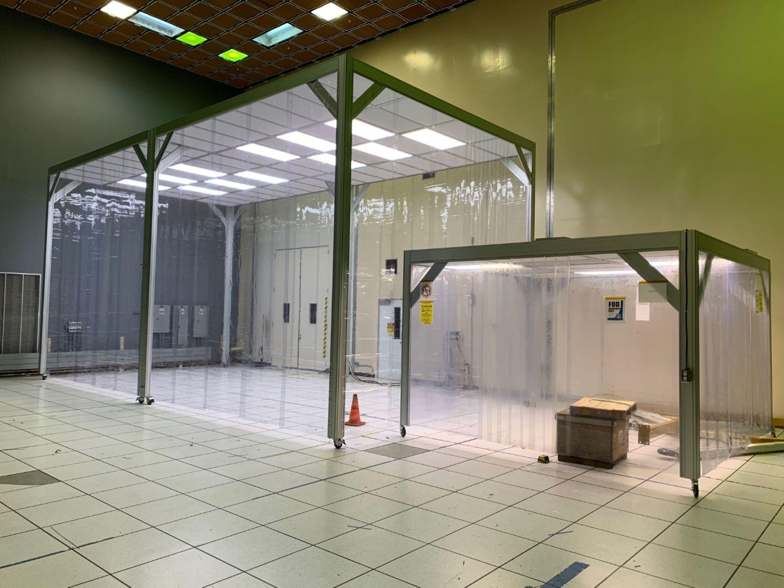 Modular cleanroom with transparent softwall panels and grid ceiling lighting.